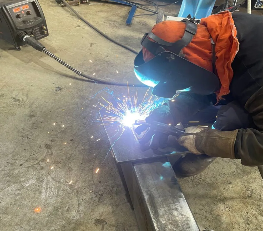 A welder laying a fillet weld on steel section, arc struck and sparks flying